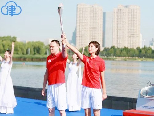 图为残奥会游泳冠军杨博尊与奥运会女排冠军李珊作为携手引燃采火棒