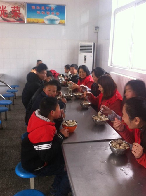 图为：孩子们开心的与助残志愿者们吃饺子
