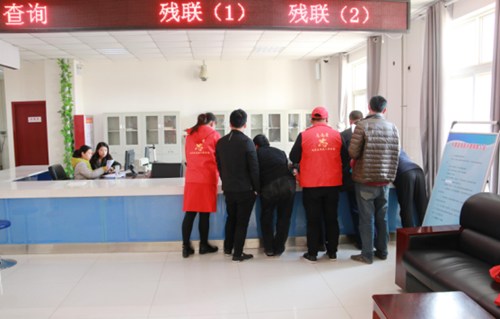 图为内黄县残联志愿者在宣誓之后来到残联办证窗口为前来办证的残疾人开展志愿服务活动