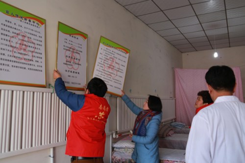 图为内黄县残联志愿者为二安单氏盲人保健按摩中心配发制度牌