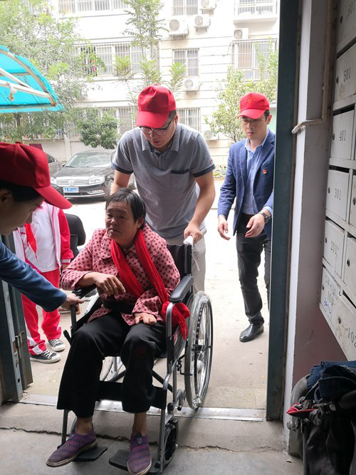 图为志愿者帮助残疾人正确使用轮椅